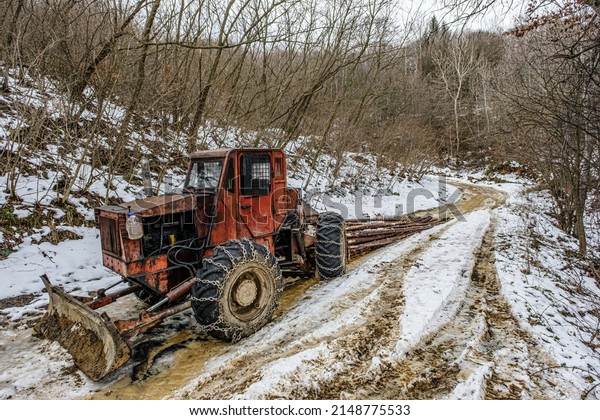 Harvester tractor snowy with wood trunks outside\
in forest.