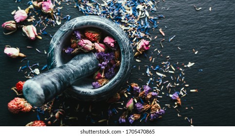 Harvesting medicinal herbs, Ayurveda, alternative medicine, dried flowers in a marble mortar on a black background