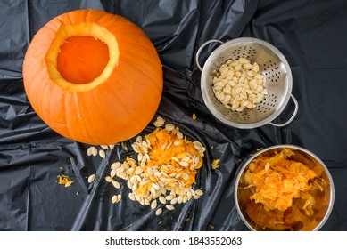 Harvesting Pumpkin Seeds, Fresh Carved Pumpkin On A Plastic Covered Table With Pumpkin Guts And Bowls
