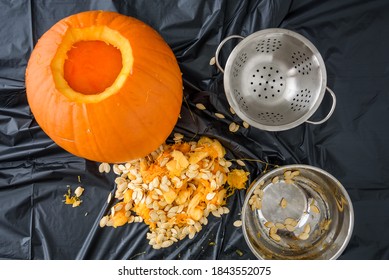 Harvesting Pumpkin Seeds, Fresh Carved Pumpkin On A Plastic Covered Table With Pumpkin Guts And Bowls
