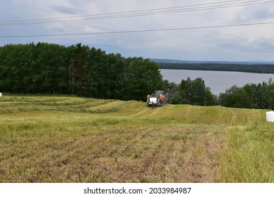 Harvesting With Tractor And Round Baler Wrapper. Lake Storsjön And The Mountains Oviksfjällen In The Background