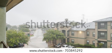 Harvey storm/hurricane heavy rain over a typical apartment complex building in suburban area at Humble, Texas, US. Parked cars on uncovered parking lot along apartment blocks. Severe weather. Panorama