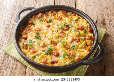 Hash brown of grated potatoes, leeks, eggs and diced smoked bacon close-up in a pan on the table. Horizontal