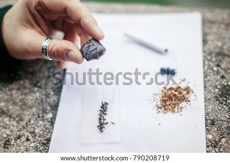Hashish set. Man preparing hashish joint rolling marijuana cigarette for smoking. Close up