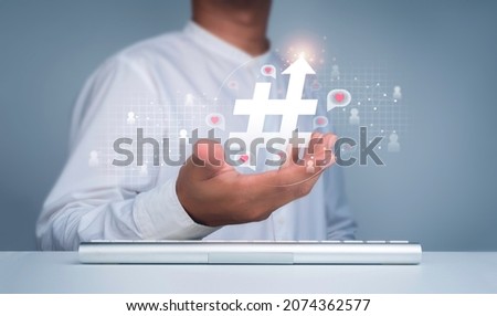 Hashtag concept.  Hashtag icon with arrow up in man's hand and people symbol with heart, love in speech bubbles floating on the social network web. Trendy, viral post and media tag marketing.
