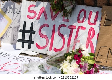 Hashtag Save Our Sisters Hand Painted Sign Or Poster Leaning Against A Wall Surrounded By Other Messages And Flowers At A Street Memorial Or Shrine Concept Gender Based Violence