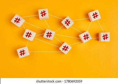 Hashtag symbols on wooden cubes connected to each other with lines on yellow background. Hashtag connection, search or trending topic in social media concept.