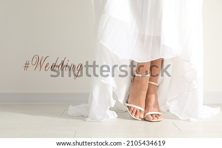 Hashtag Wedding and young bride wearing beautiful dress near light wall, closeup