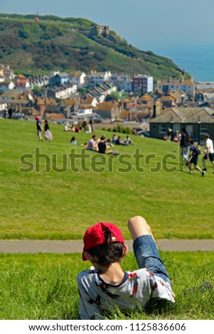 Hastings,East Sussex/UK 07/05/18 A beautiful May Day bank holiday Monday. A young lad relaxes on the West Hill with views of the Old Town and East Hill with its funicular railway in the distance