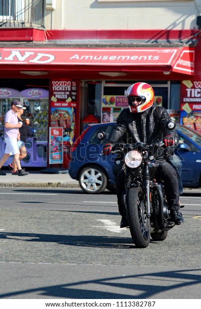 Hastings,East Sussex/UK 07/05/18 Bike 1066\
the annual May Day bike run to Hastings. A black Triumph motorbike\
with pillion passenger arrives on Hastings seafront to join\
thousands of other\
motorcycles