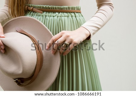 Hat, beige blouse and turqoise pleats skirt on light street backgraund.  Fashion and stylish concept.