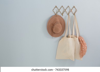 Hat, grocery bag and scarf hanging on hook against white wall - Powered by Shutterstock