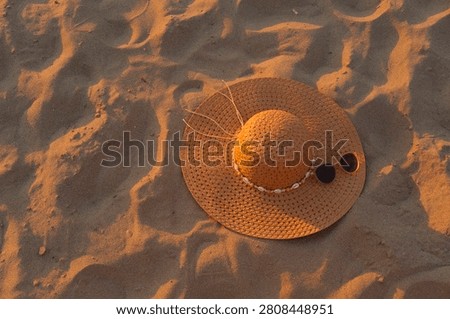 Hat on sand with a ball under sun, beach scene showing leisure, vacation and relaxation in warm light for a relaxed outdoor mood