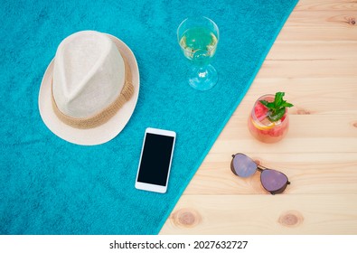 Hat, Smartphone, Glass Of White Wine, Glass Of Watermelon Lemonade And Sunglasses On Blue Towel On Wooden Surface. Top View, Copy Space.