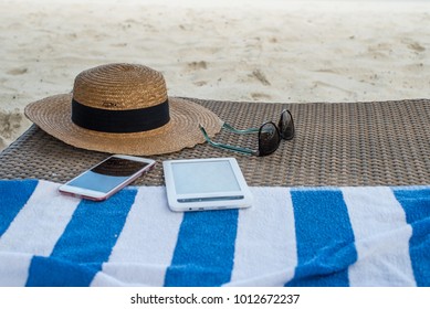 hat, sunglasses, e-book and mobile phone at the towel on sand near ocean on maldives - Powered by Shutterstock