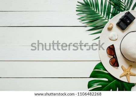 Hat, sunglasses, film camera, sea star, green plam leaves arranged on wooden baclground. Summer holidays vacation concept. Poster banner, postcard template.