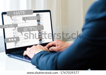 Hate Speech concept. a man works at a laptop and receives messages with notification icons of bullying on social networks and hatred on the Internet
