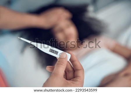 I hate it when my babys unwell. Shot of an unrecognizable man taking his daughters temperature at home.