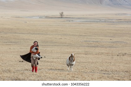 Hatgal, Mongolia, 3rd March 2018: Mongolian Kid Carrying A Baby Sheep  In A Steppe Of Northern Mongolia