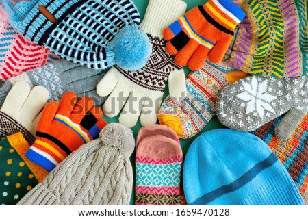 A lot of hats, gloves, mittens. Warm clothes in the form of knitted hats, mittens, gloves, scarves for the cold seasons. Multi-colored clothes for autumn and winter.