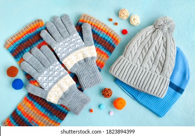 Hats, gloves and a scarf on a textured background. Warm clothes for autumn and winter in the form of hats, gloves and a scarf. Fashionable set of clothes made of hats and gloves.