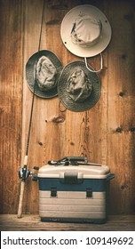 Hats hanging on wooden wall with fishing equipment