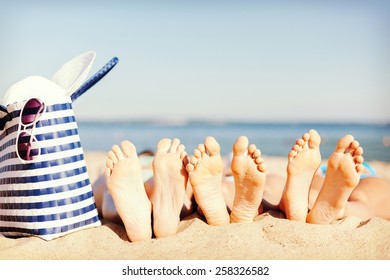 Hüte und Sommerkonzept - drei Frauen liegen am Strand mit Strohhut, Sonnenbrille und Tasche