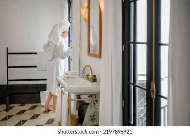 HAVA, CUBA - Feb 18, 2022: A Woman In A Bathrobe And A Towel On Her Head Inside A Bathroom Looking Out The Window