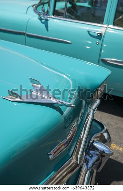 HAVANA - CIRCA JUNE, 2011: The hood\
ornament of 1953 Chevrolet BelAir gleams in the tropical sun next\
to another vintage American car in complementary\
blue.