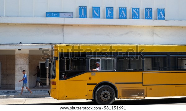 HAVANA CITY, CUBA - NOVEMBER 2016: A yellow\
public bus on the street of. Behind is the cinema theater \'Infanta\'\
in Central Havana.
