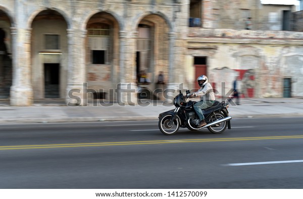 HAVANA - CUBA /\
03.08.2017: Motor driver speeding along the road at El Malecon\
Boulevard, Havana, Cuba