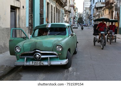 HAVANA - CUBA / 09.03.2017: Havana street scene, american classic car, cycle rickshaw and people, historic buildings