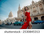 Havana, Cuba, 18th April 2024: National Capitol of Cuba with classic colorful cars and woman in red dress