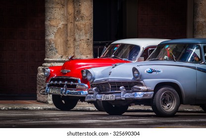 HAVANA, CUBA - CIRCA AUGUST, 2015: Old 1950s cars stopped at a city crossroads in Havana in front of a crumbling colonial building
