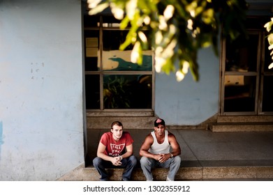 Havana,  Cuba - Circa Jan 2015: Two People Sitting On The Sidewalk In Front Of The Children's Hospital
