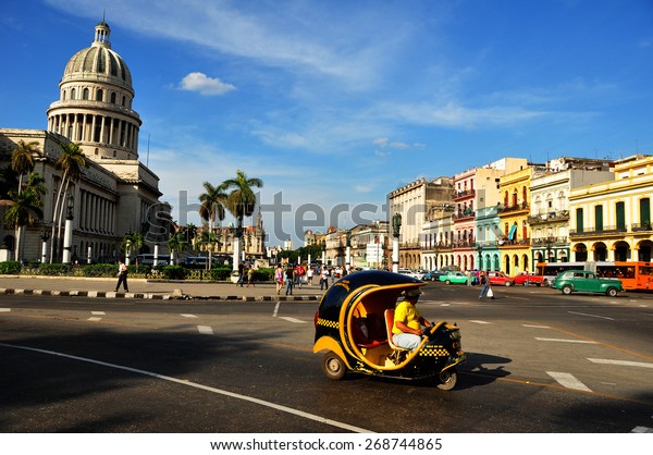 HAVANA, CUBA - DECEMBER 15 2014: Moto taxi in\
the center of Havana with the Capitolio as background. The US has\
announced changes to its policy with\
Cuba