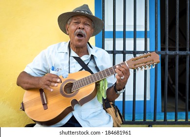 HAVANA, CUBA - FEBRUARY 25, 2014: Street Musician Playing Traditional Cuban Music On An Acoustic Guitar For The Entertainment Of Tourists In A Typical Colorful Old Havana Street