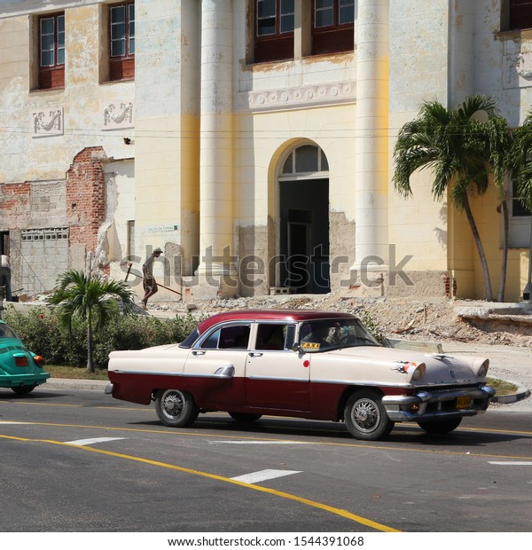 HAVANA, CUBA - FEBRUARY 26, 2011: People drive old\
cars in Havana. Cuba has one of the lowest car-per-capita rates (42\
per 1000 people in\
2015).