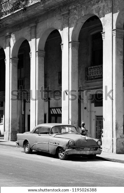 HAVANA, CUBA - FEBRUARY 27, 2011: People walk past\
Classic American car in Havana, Cuba. Recent change in law allows\
the Cubans to trade cars\
again.