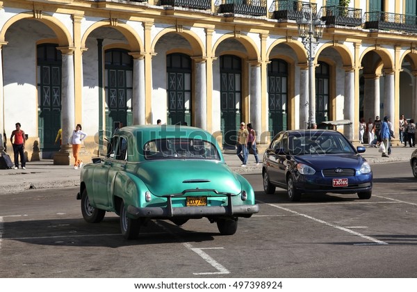 HAVANA, CUBA - JANUARY 30, 2011:\
People walk by old American car parked in Havana. Cuba has one of\
the lowest car-per-capita rates (38 per 1000 people in\
2008).