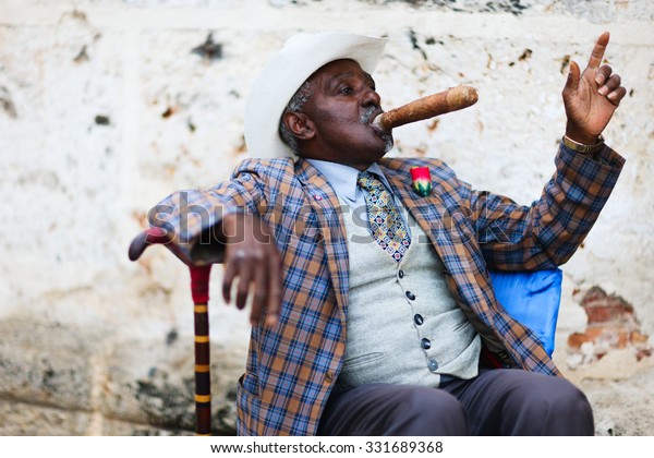 HAVANA, CUBA - JULY 17,\
2013: Cuban man posing for photos while smoking big cuban cigar in\
Havana, Cuba.