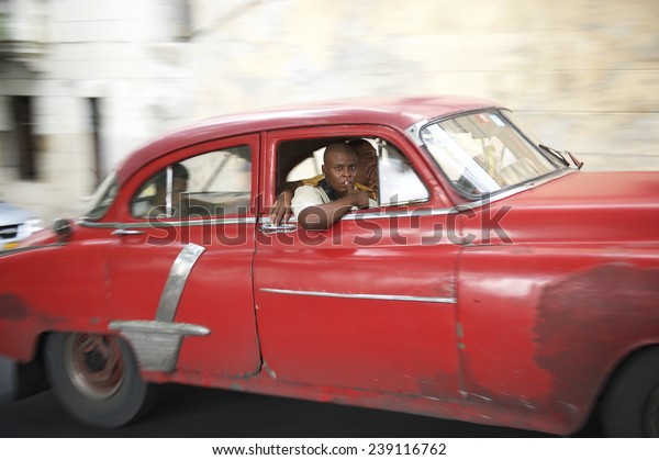 HAVANA, CUBA\
- JUNE, 2011: Vintage American car serving as taxi drives with\
passengers along a street in Central\
Havana.