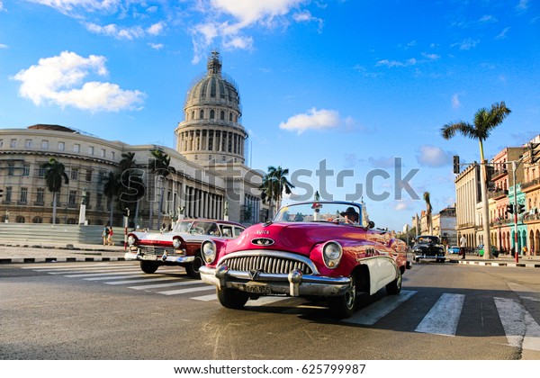 Havana, Cuba -\
March 2017; A pink oldtimer in front of the Capitolio in Havana.\
Havana is the capital of\
Cuba.