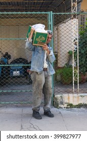 Havana, Cuba - March 7, 2016: An Unidentified Cuban Man Carrying A Box On His Shoulders Posing In Front Of A Chain Link Fence 