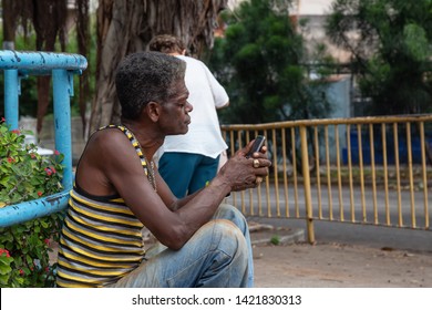 Havana, Cuba - May 15, 2019: Cuban Man Is Using A Cell Phone At The Wifi Hotspot In The Streets Of The Old Havana City During A Wet Rainy Day.