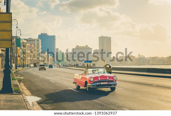 Havana, Cuba - October 04, 2018: Retro Style -\
American red pink 1956 Pontiac convertible vintage car on the\
promenade Malecon in the evening sun in Havana City Cuba - Serie\
Cuba Reportage