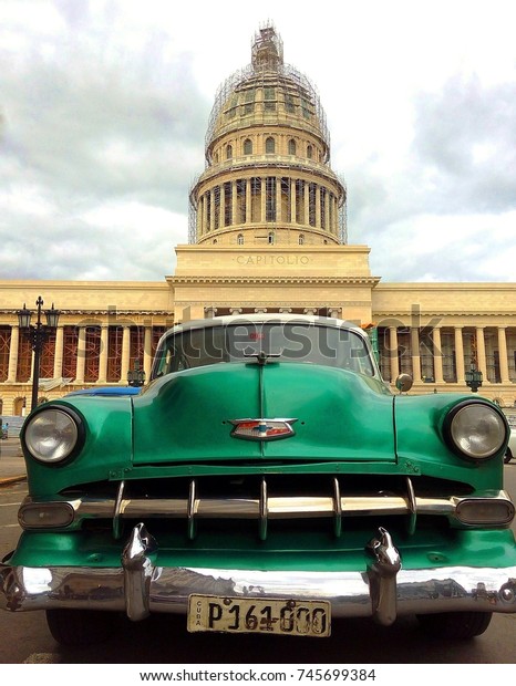 HAVANA,\
CUBA – OCTOBER 30, 2017: Close-up of vintage classic American car\
Chevrolet in front of El Capitolio, famous Havana landmark, against\
cloudy sky in Habana Vieja / Old Havana, Cuba\

