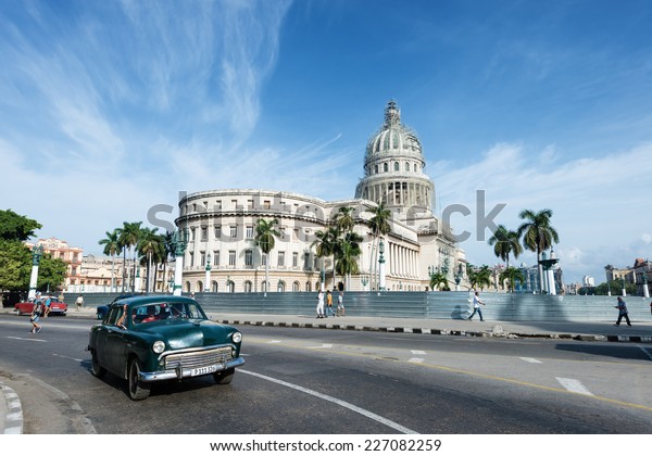 HAVANA, CUBA - OCTOBER 8, 2014: Old classic American\
green car rides in front of the Capitol. Before a new law issued on\
October 2011, Cubans could only trade cars that were on the road\
before 1959. 
