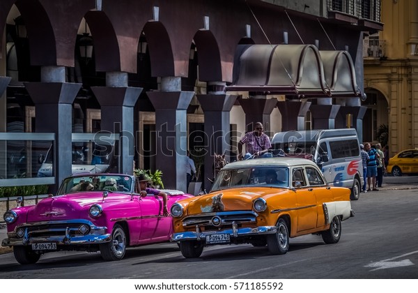 Havana, Cuba - September 14, 2016:\
HDR - American orange Buick and pink Chevrolet Cabriolet classic\
car on the main street in Havana Cuba - Serie Cuba\
Reportage