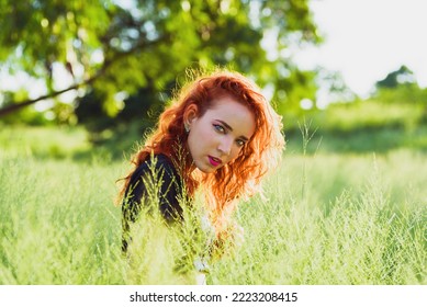 Havana, Cuba. September 18, 2021. Young Redhead Woman In Tall Grass Field Looking At Camera During Sunset 